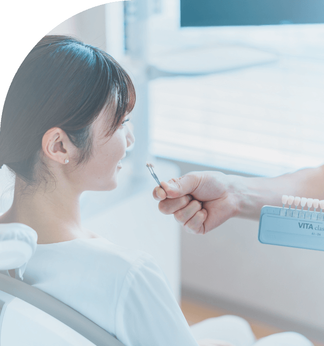 シェードガイドを使い、天然歯に最も合う、セラミックの色を選んでいる歯科医師