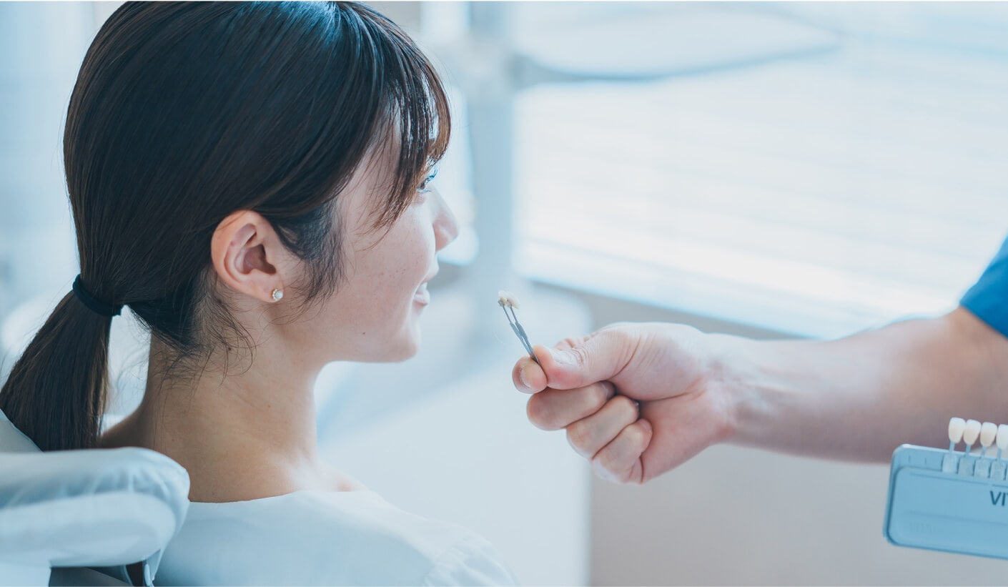 シェードガイドを使い、患者様の天然歯に合うセラミックの色を慎重に選んでいる歯科医師