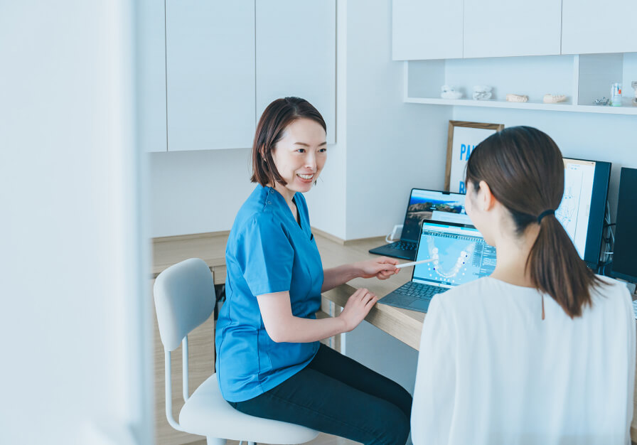 治療前の不安を解消するため、女性歯科医師が笑顔で分かりやすく説明しているカウンセリング風景